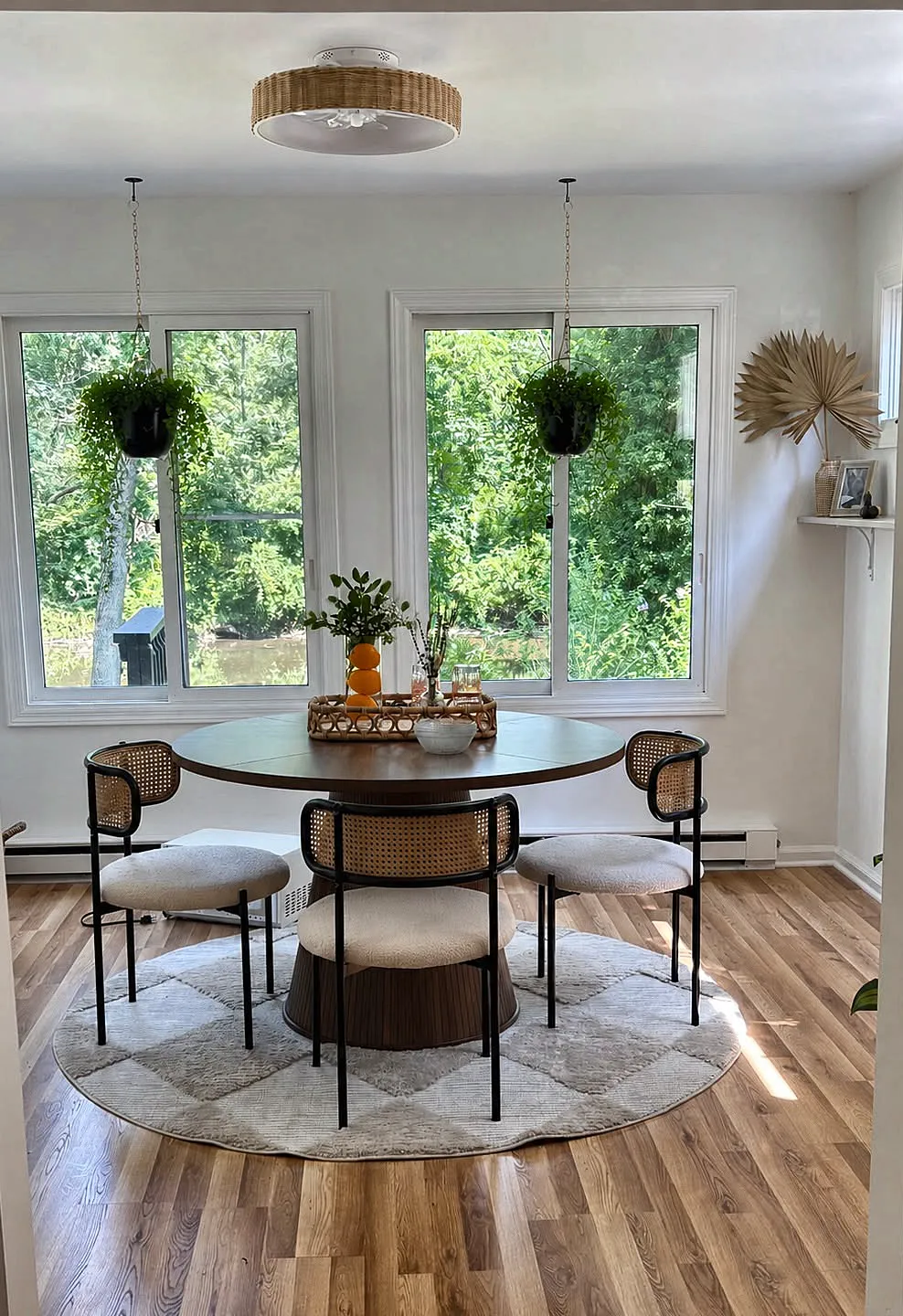 Breakfast nook with a round pedestal table and cane back chairs beneath two windows