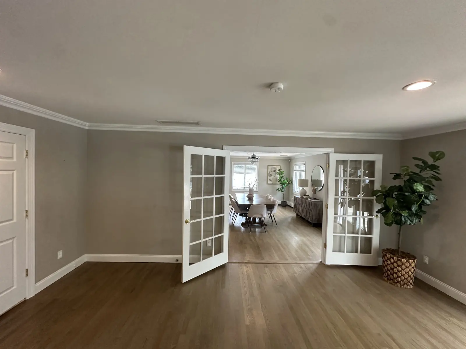 Open interior with French doors, crown molding, and refinished hardwood leading to a dining room