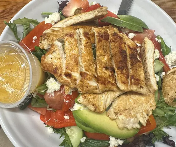 Sliced grilled chicken over mixed greens with feta and avocado